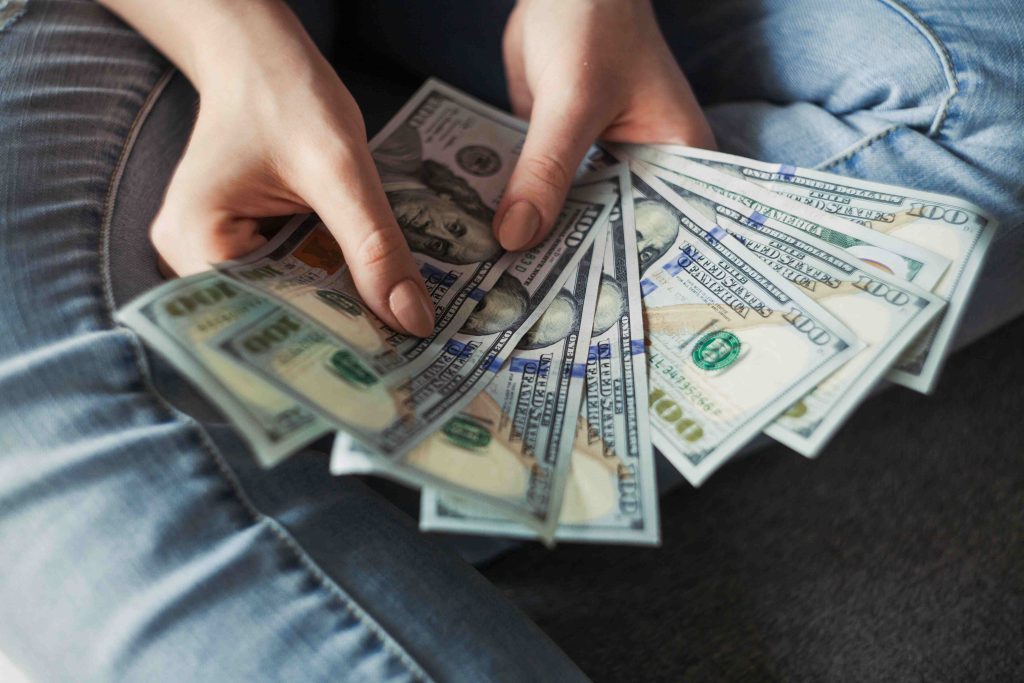 A person organizing finances with a calculator, notebook, and stacks of cash, symbolizing effective budgeting strategies and financial planning for 2025